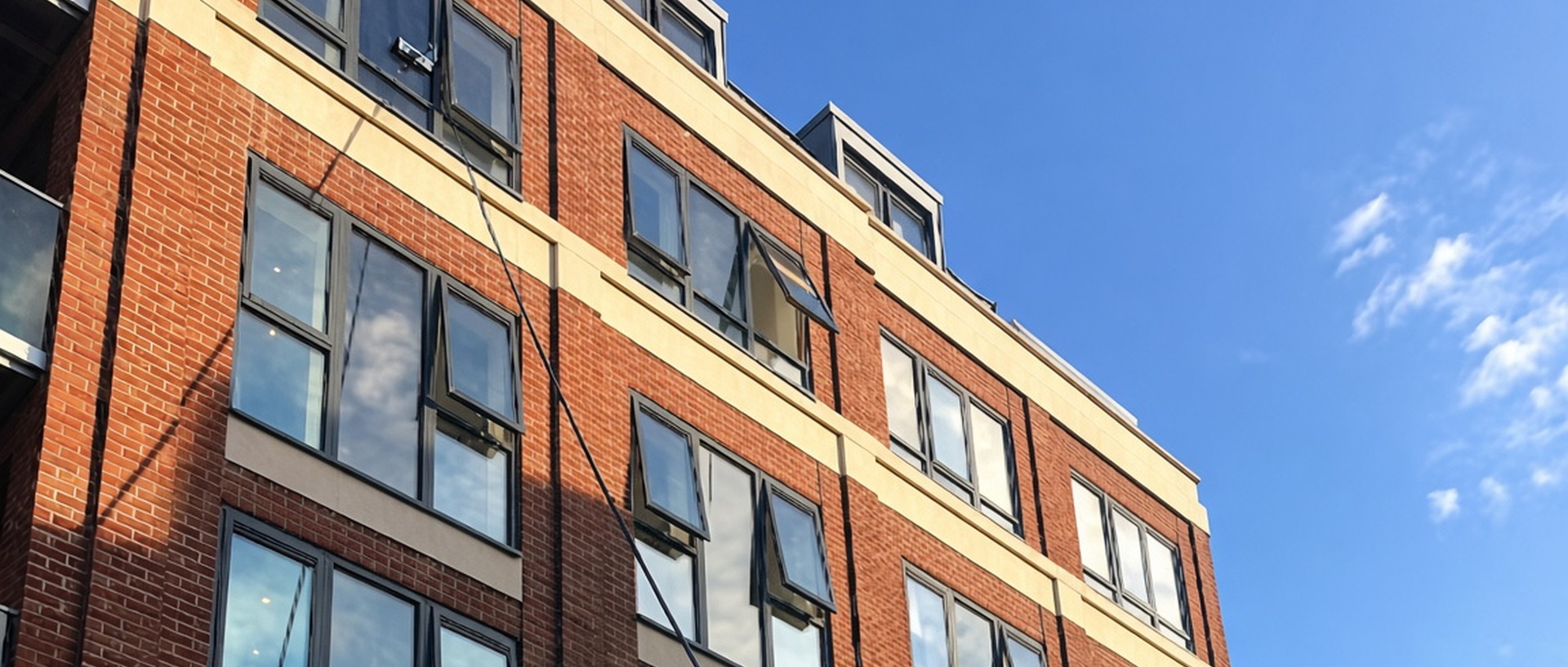 DPC window cleaner using a water-fed pole on a brick apartment building in Woodford Green